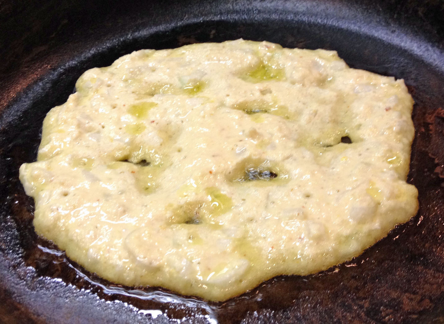 Batter spread on the pan with little holes for oil.